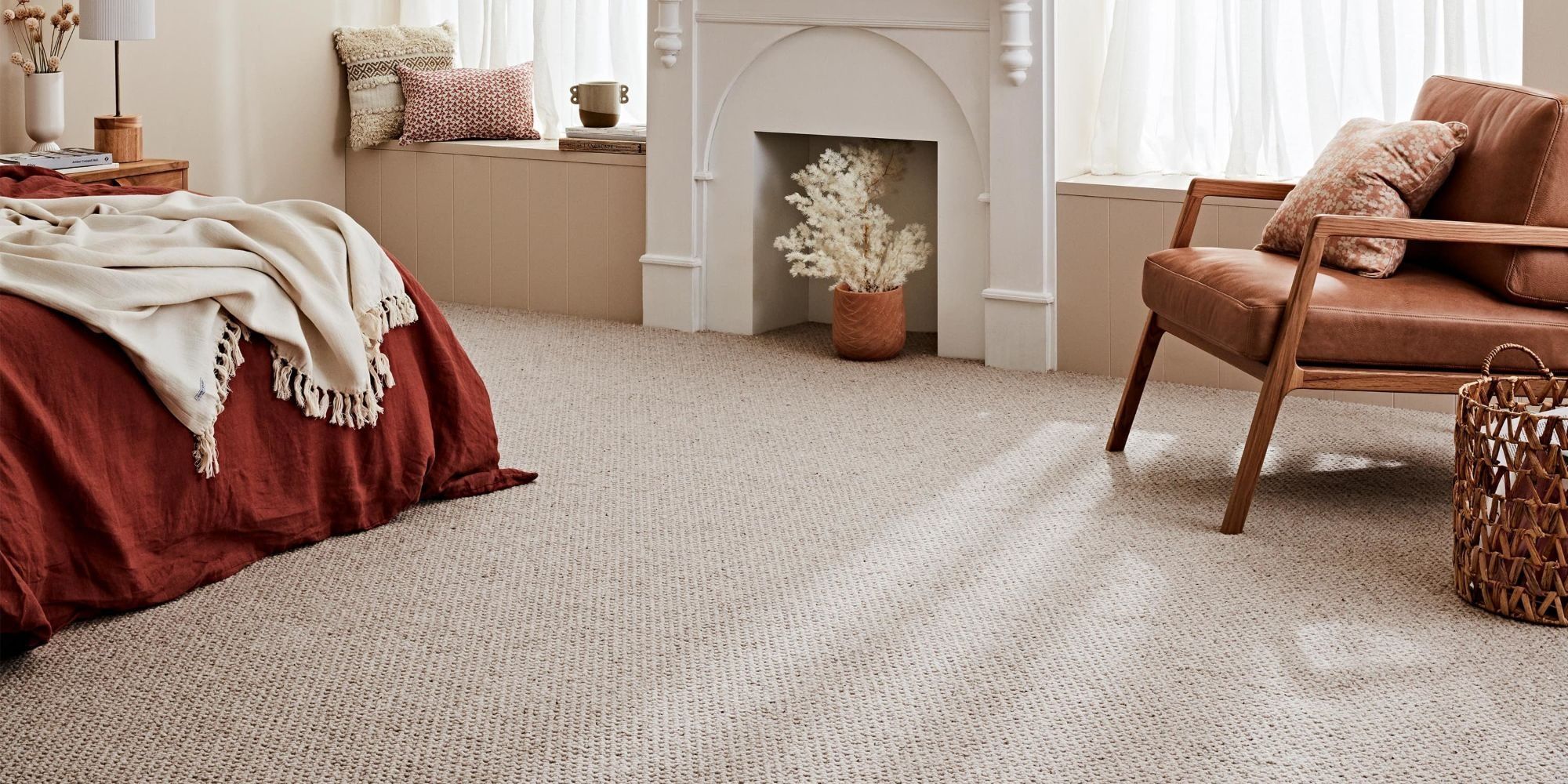 A bedroom carpeted wall to wall in a beige loop-pile carpet, sunlight falling across it
