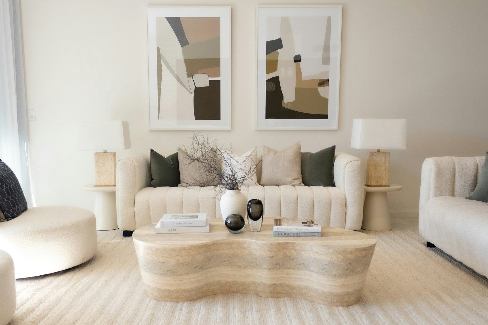A cream living room where a large rug runs under the front legs of the sofa and chairs