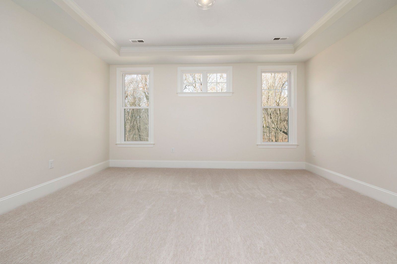 An empty bright room with new ivory wall-to-wall carpet running to the skirting