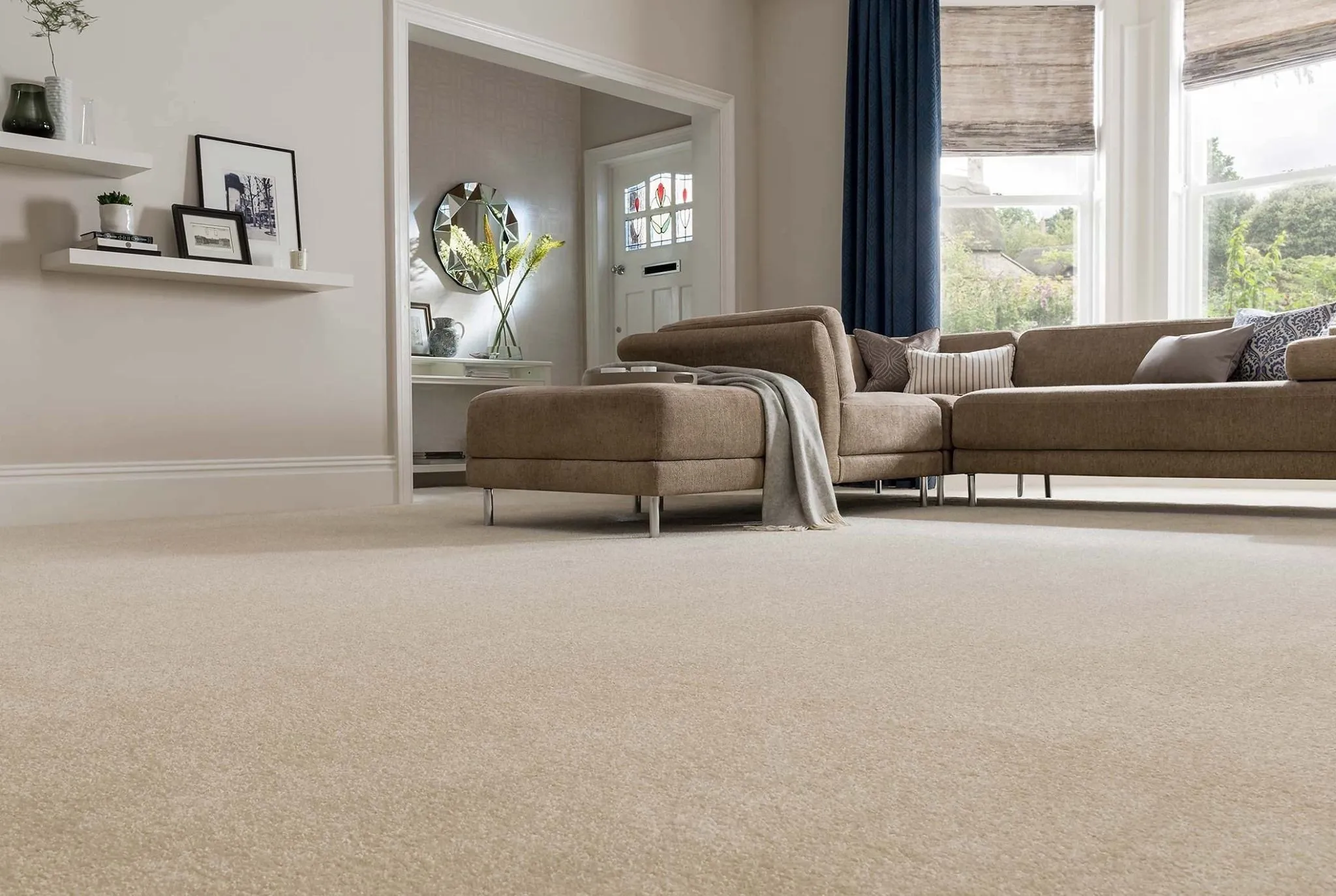 A living room with plush beige wall-to-wall carpet running from the sofa to the foreground