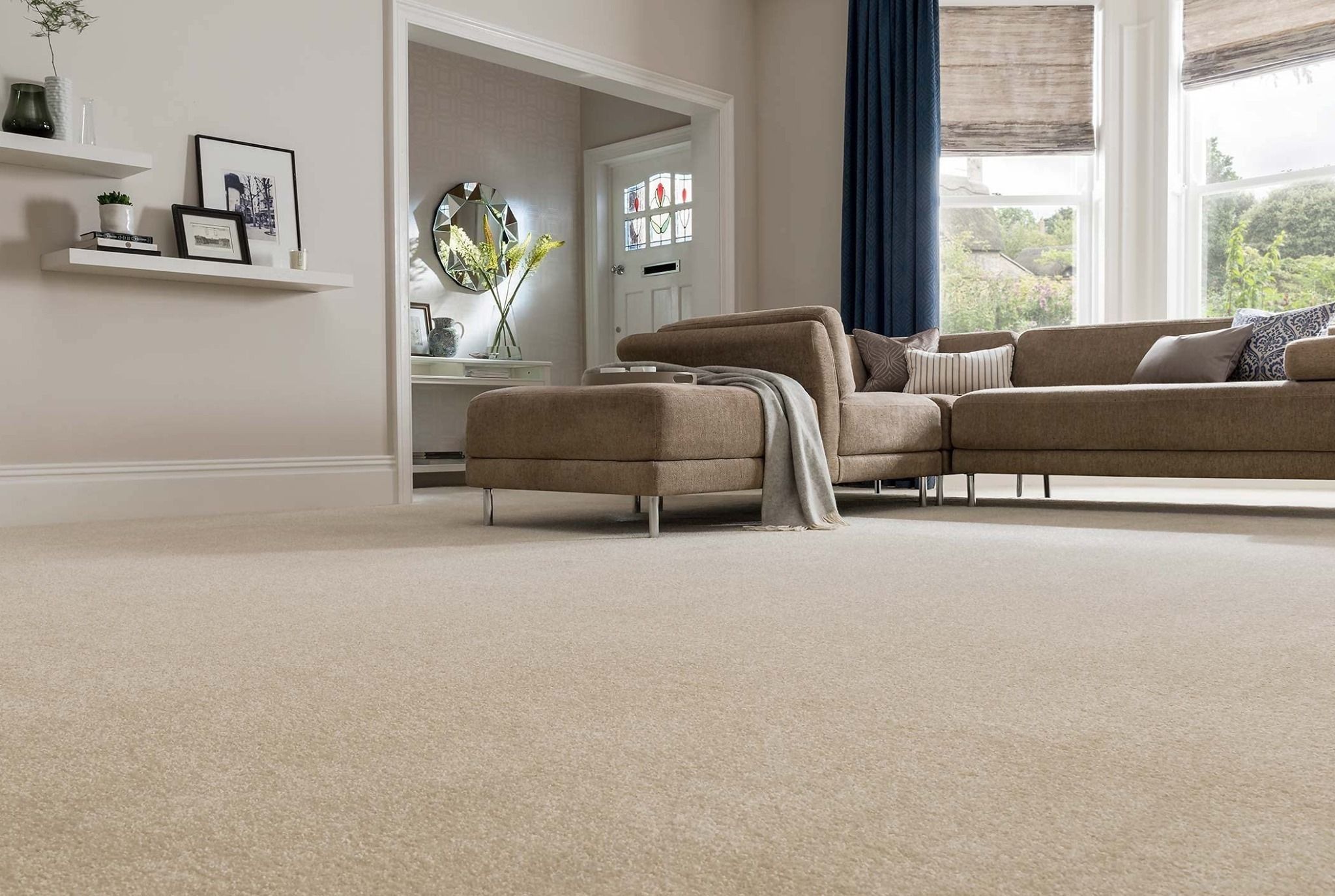 A living room with plush beige wall-to-wall carpet running from the sofa to the foreground
