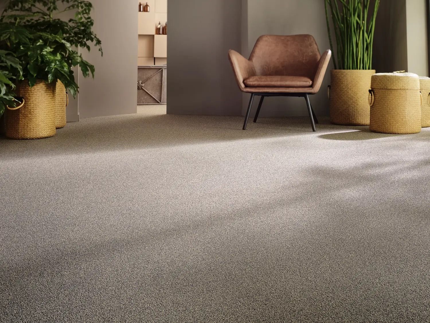 A lounge floored wall to wall in a speckled taupe carpet, a leather chair and woven baskets on it