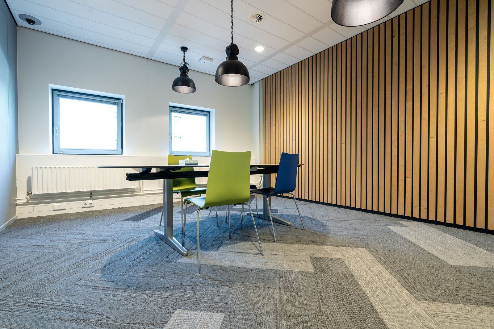 A meeting room floored in grey carpet tiles laid in a herringbone pattern
